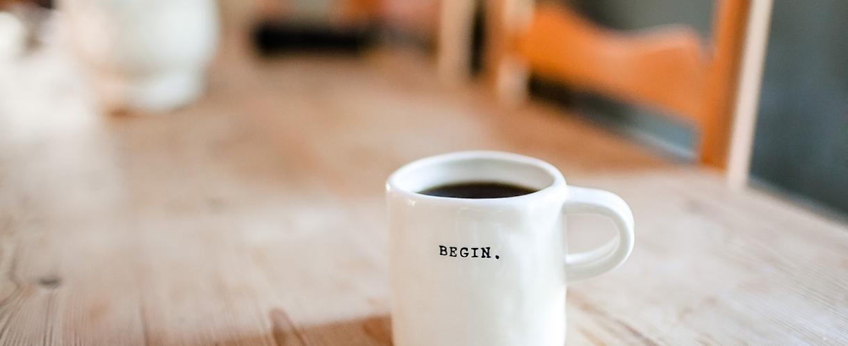 Coffee cup on a desk with the word 'Begin' on it.